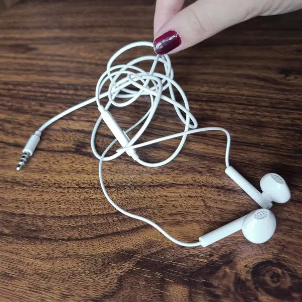 El karmaşık kulaklıkları alır. Eller akıllı telefon için kulaklık telini çözsün. Metin için arkaplan, yer.