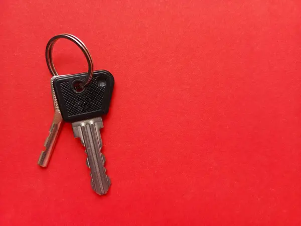 Kırmızı arka planda iki daire anahtarı. Emlakçılık. Bir daire alıyorum. Bir daire, bir ev satışı. Reklam için arka plan, metin için yer. Bir emlakçı. Kiralık konut.