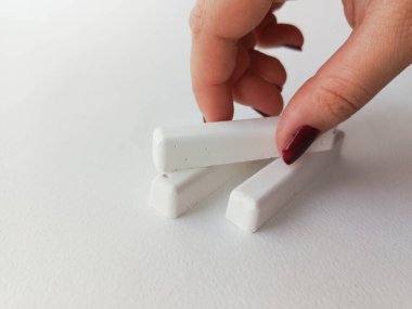 Bir el okul tebeşirini masadan alır. Reklam arkaplanı, metin için boşluk.