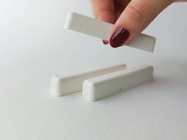 Bir el okul tebeşirini masadan alır. Reklam arkaplanı, metin için boşluk.