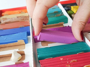 Bir el, plastik bir paketten mor bir parça plasticin alır. Okulda heykel dersi, anaokulu konsepti. Geçmişi. Metin için yer.