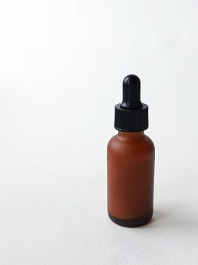 Beyaz arka planda pipetli kahverengi bir kozmetik ürünü şişesi. Reklam kremi, serum, metin için yer.