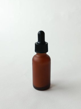 Beyaz arka planda pipetli kahverengi bir kozmetik ürünü şişesi. Reklam kremi, serum, metin için yer.