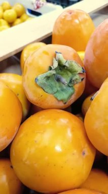 Bir el, yakın plandaki çekmeceden bir hurma alır. Dikey video 9: 16. Meyve ve sebze pazarı reklamı için parlak bir arka plan.