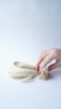 Bir kuaförün kadın eli uzatma için bir at kuyruğu saçı ayırır. Keratin kapsülleri yakın plan saç telleri üzerinde. Dikey video 9: 16. Doğal sarı saç kesimi..