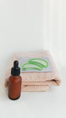 Pipetli küçük kahverengi bir şişe, pembe bir havlu, beyaz arka planda göz bantları. Geçmişi. Yüz bakım kozmetik seti.