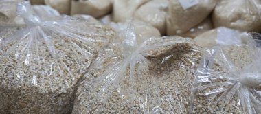 İçi arpa dolu çantalar yakınlarda yetişiyor. Şeffaf torbalarda arpa. Toptan ve perakende alışverişi. Gıda ürünleri için artan fiyatlar.