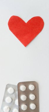 Kırmızı kalp ve beyaz arka planda hapları olan destekçiler. Kartpostal için arka plan. İlaç sanayisi. Eczane reklamı.