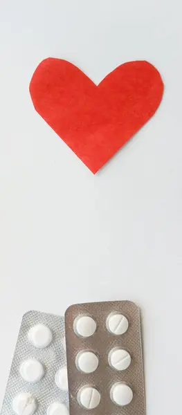 Kırmızı kalp ve beyaz arka planda hapları olan destekçiler. Kartpostal için arka plan. İlaç sanayisi. Eczane reklamı.