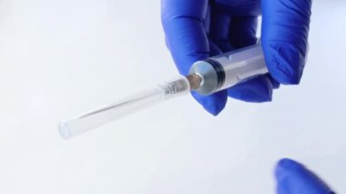Tıbbi eldivendeki eller şırınga iğnesinden kapağı çıkarır. Şırınga açılıyor. Çocuk konsepti için rutin aşılar. Aşılama. Steril tıbbi eşyalar. İğne için şırınga iğnesini açın. Antibiyotikler.