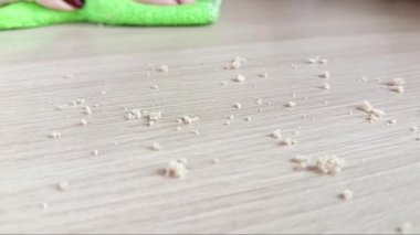 Bir kadın masadaki kırıntıları temizler. Öğle yemeğinden sonra mutfak masasındaki kırıntıları bezle silen bir el. Yemeklerden sonra mutfağı temizliyorum.. 