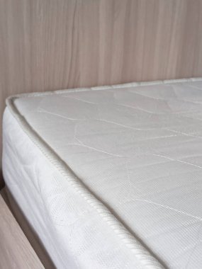 Yatağın üzerinde beyaz ortopedik yatak. Yeni mobilyalar. Rahat bir uyku için bir yatak..