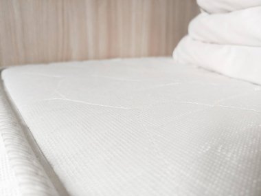 Beyaz bir battaniye, yatak çarşafları yatağın üzerinde yatıyor. Otelde temiz çarşaf..