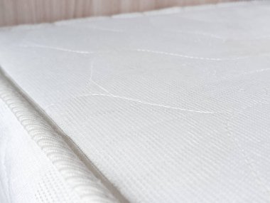 Yatağın üzerinde beyaz ortopedik yatak. Yeni mobilyalar. Rahat bir uyku için bir yatak..