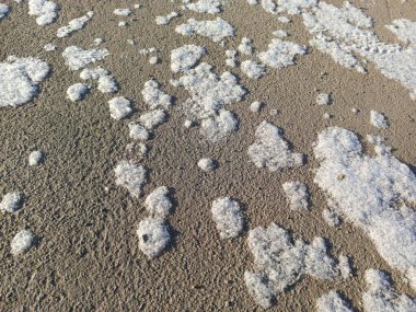 Yerde kar taneleri uzanıyor. İlkbaharda kar eriyor. Şehirdeki ilk kar..