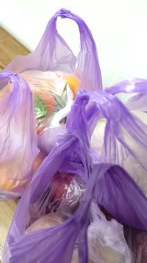 Plastik poşetler ahşap bir bankta duruyor. Süpermarkette bir ay market alışverişi. Ağır çantalar. Mor plastik torbalar..