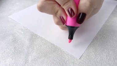 Beyaz bir kağıt parçasına pembe keçeli kalemle yazan bir kadın. Bir plan ve hedefler çiziyorum. Hafta planlama. 
