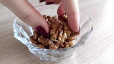 Bir kadının eli fındığı yakın plan çekimde alır. Cevizler kabuktan soyulmuş..