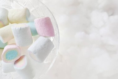 Bardakta renkli şekerlemeler, beyaz bulutların arka planına karşı şeffaf şeker kasesi, üst manzara, toplantı, yazı için yer. Lezzetli marmelat. Tanıtım fotoğrafı..