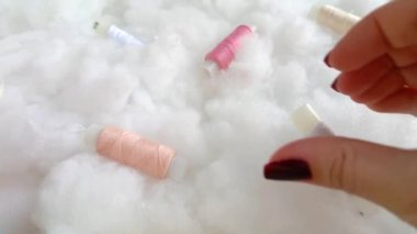 Kalp şeklindeki kadın elleri kar beyazı yumuşak dolgunun arka planında ipek böceği kozasını tutuyor. Yastık ve battaniye doldurucu. İpek böceği iplikleri.