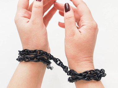 Bir kadının kolları beyaz arka planda siyah metal bir zincirle sarılmıştır. Psikolojik travma ve depresyon kavramı. Sınırlamalar. 