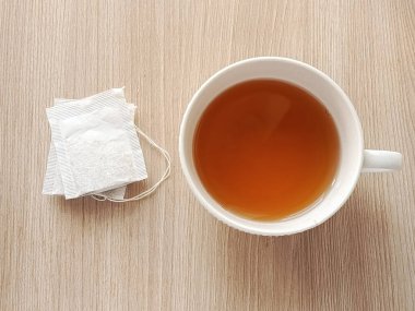 Mutfak masasında beyaz bir fincan sıcak çay ve iki poşet çay var. Siyah, yeşil çay poşetlerinin faydaları. Sabahları sıcak bir şeyler içerim..