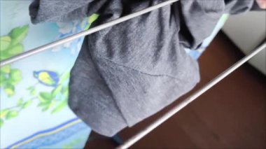 Kadınların elleri temiz giysileri kurutucuya asar. Bir kadın çamaşırları ipe asıyor. Bir şeyleri kurutmak. Çamaşır. Çamaşır yıkama ve kurutma işlemi..