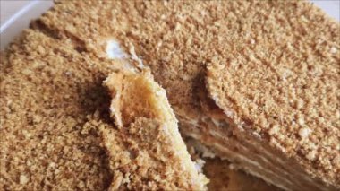 Kesilmiş pasta masanın üzerinde, beyaz bir tabakta bir parça pastanın yanında. Tereyağlı, pastalı ve kırıntılı bal pastası..