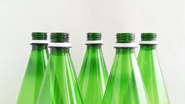 Beyaz arka planda yakın plan yeşil plastik şişeler. Şişe su. Su günü. Şişeler ve plastik atıklar sınıflandırılıyor.