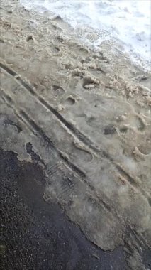 Yolda karla karışık. Islak kar asfaltta erir. Isınma. Eriyen kardaki ayak izleri. Mart ve Nisan aylarında sıcak hava. Sellerin nedeni bir kavramdır..