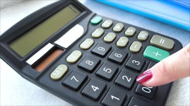 Bir kadının eli hesap makinesindeki sayıları sayar. Muhasebecinin işi. Finansal istatistikler. Ekonomik gelişme. İpotek. Vergiler. Emeklilik birikimi. Hesaplamalar.