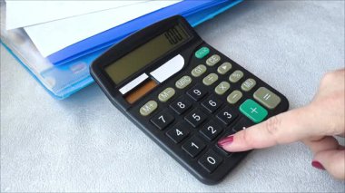 Kadın hesap makinesinin düğmelerine basıyor. Bir kadın hesap makinesiyle hesap yapar. Banka mı? İpotekler, borçlar. Finansal krediler. Mali okuryazarlık.