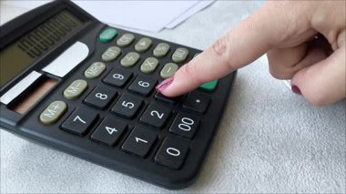 Bir kadının eli hesap makinesindeki sayıları sayar. Muhasebecinin işi. Finansal istatistikler. Ekonomik gelişme. İpotek. Vergiler. Emeklilik birikimi. Hesaplamalar.