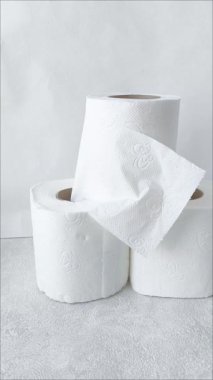 Masanın üzerinde üç rulo beyaz tuvalet kağıdı var. Birincil selülozdan yapılmış küçük tek kullanımlık havlular. Kağıt peçeteler..