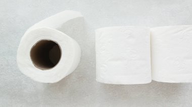 Üç rulo beyaz tuvalet kâğıdı masanın üstünde, üst tarafta. El için tek kullanımlık kağıt havlu. Hijyenik peçete..
