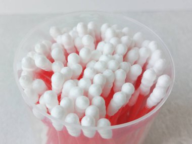 Plastik bir kapta tek kullanımlık pamuklu çubuklar. Pamuklu çubukların promosyon fotoğrafı. Kulak temizliği..