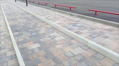 Caddedeki kaldırım taşlarından yapılmış merdivenin yanında kırmızı metal bir çit. Kaldırımlar çitlerle çevrili. Kentte yollar ve kaldırımlar inşa ediliyor.
