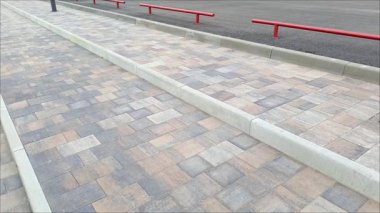 Caddedeki kaldırım taşlarından yapılmış merdivenin yanında kırmızı metal bir çit. Kaldırımlar çitlerle çevrili. Kentte yollar ve kaldırımlar inşa ediliyor.