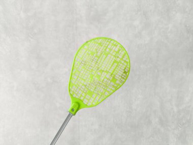 Gri arka planda yeşil bir sinek ezici. Evlerdeki sineklerin kontrolü. Metin için boşluk.