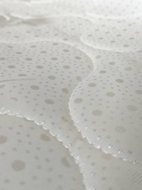 Beyaz yorganlı su geçirmez yatak. Ortopedik yatak, doku