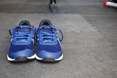 Blue sneakers on the floor of a gymnasium with space for texting. clipart