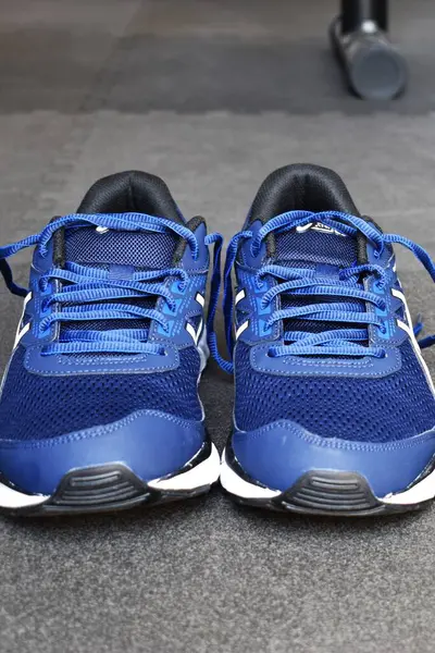 Spor salonunun zemininde mesaj atmak için yeri olan mavi spor ayakkabılar..