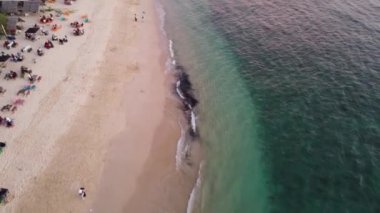 Sahilde dalgaların tadını çıkaran turistlerin hava manzarası. Manzaralı tropik adalarda seyahat eden mutlu insanlar.