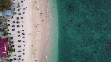 Sahilde dalgaların tadını çıkaran turistlerin hava manzarası. Manzaralı tropik adalarda seyahat eden mutlu insanlar.