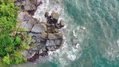 Deniz kıyısındaki kayaların drone kamerası, güzel deniz yüzeyi, kayaların üzerine çarpan inanılmaz deniz dalgaları..
