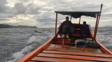 Aceh, Endonezya - 24 Temmuz 2024: Balıkçılar kötü hava şartları nedeniyle balıkçılığı iptal ettiler. Fırtına ve büyük dalgalar sırasında hareket eden tekneden deniz pelerini. Balık ve balıkçılık kavramı.