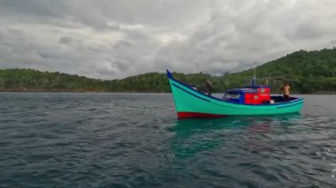 Aceh, Endonezya - 24 Temmuz 2024: Balıkçılar kötü hava şartları nedeniyle balıkçılığı iptal ettiler. Fırtına ve büyük dalgalar sırasında hareket eden tekneden deniz pelerini. Balık ve balıkçılık kavramı.