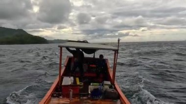 Aceh, Endonezya - 24 Temmuz 2024: Balıkçılar kötü hava şartları nedeniyle balıkçılığı iptal ettiler. Fırtına ve büyük dalgalar sırasında hareket eden tekneden deniz pelerini. Balık ve balıkçılık kavramı.