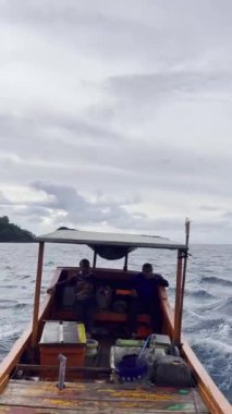 Aceh, Endonezya - 24 Temmuz 2024: Balıkçılar geleneksel tekneyle balığa gider. Hareket halindeki tekneden deniz pelerini. Balık ve balıkçılık kavramı.