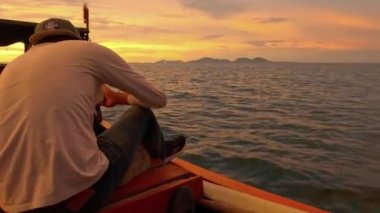 Aceh, Endonezya - 3 Temmuz 2024: Balıkçılar akşam günbatımında bir balıkçı teknesinde rahatça oturuyorlar. Balık ve balıkçılık kavramı.